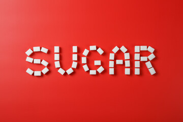 Sugar word made from sugar cubes on red background