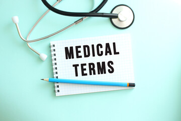 White notepad with the words MEDICAL TERMS and a stethoscope on a blue background.