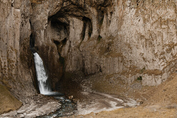 A high stormy waterfall flowing down in the massive rocks of Djily-su on an autumn day. Journey through the mountain beauties of the Caucasus

