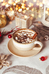 Fototapeta na wymiar A cup of cocoa with marshmallows on a New Year's table on a white background. Cozy Christmas vertical card