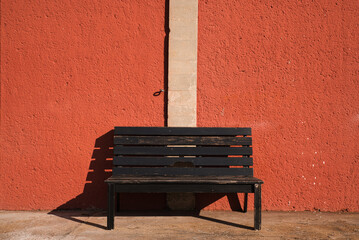 Aufnahme einer roten Wand mit einer Bank im Vordergrund