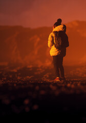 Lone teenage girl in a white jacket and backpack stands in a misty rocky landscape during sunset. Rear view. 3D render.