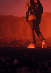 Boy in jeans and sneakers with backpack in a misty rocky landscape during sunset. Rear view. 3D render.