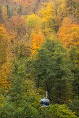 Multicolor autumn trees and ski lift in the mountains. Autumn misty landscape with ski lift. Fog in the mountains.