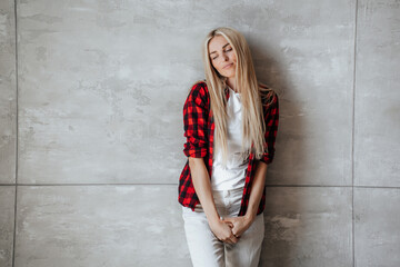 Lonely blonde caucasian young woman in plaid shirt standing at home in frustration leans on marble wall looks down sadly. Overloaded Scandinavian girl feels fatigue. Mockup, failure mistake.