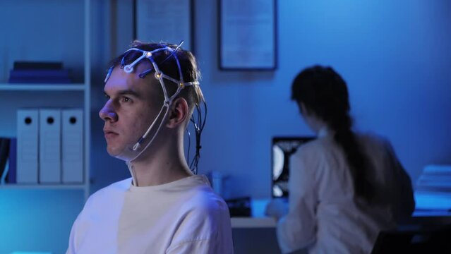 EEG topographer for examining brain, doctor making electrogram of scalp activity. Researching of brain work, man riding bicycle in electroencephalography headset. Rehabilitation after damage in sport.