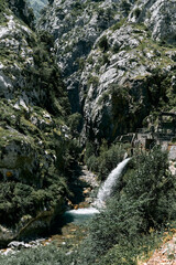 old small hydroelectric power station hidden between the rocks of the big mountains next to the water of the river, ruta del cares asturias, spain