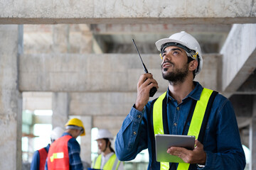 maintenance manager using walkie-talkie to communicate safety and quality control policy with...