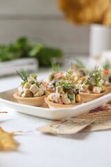 Vegetarian Olivier salad in tartlets, festive table, white background 
