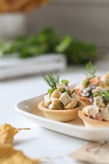 Vegetarian Olivier salad in tartlets, festive table, white background 