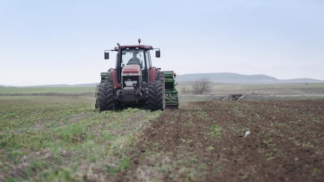Farmer with tractor seeding, sowing crops at agricultural fields, slow motion