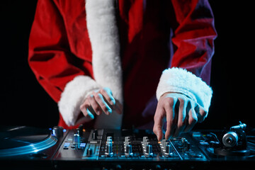 Christmas DJ in Santa Claus costume playing music in night club. Disc jockey wearing traditinal red...