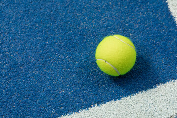 Tennis ball in a blue floor in a panel court