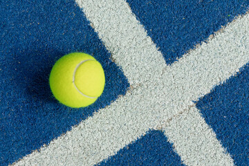 Tennis ball in a blue floor in a panel court