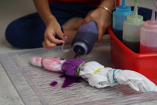 Little kid enjoying making a craft, using different colour ink to paint a tie-dyed cloth. Kids arts and crafts, Tie dye—art and craft DIY for children concept.
