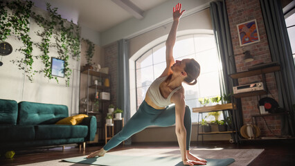 Young Athletic Woman Exercising, Stretching and Practising Yoga in the Morning in Bright, Sunny and Stylish Home Living Room. Healthy Lifestyle, Fitness, Wellbeing and Mindfulness Concept.
