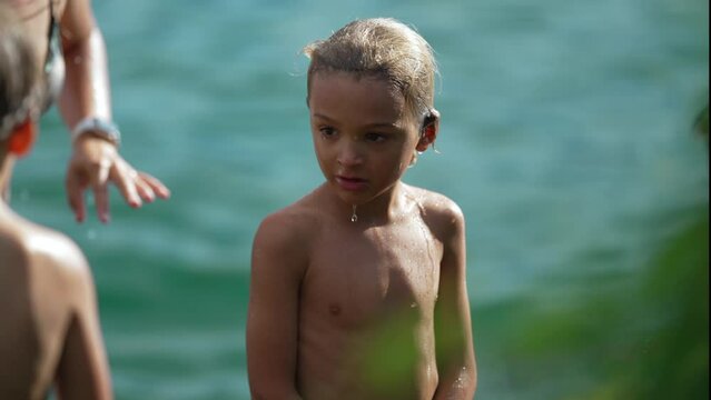 One pensive small boy standing outdoors. Wet child shivering outside shirtless after bathing at lake. Contemplative kid thinking outside in nature