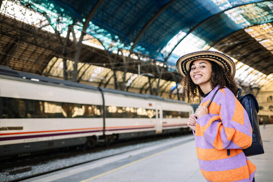 Young black woman traveler with backpack in the railway, Backpack and hat at the train station with a traveler.