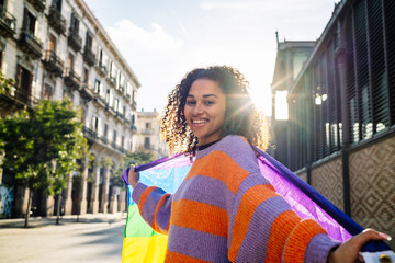 Confident black woman outdoors holding a rainbow flag