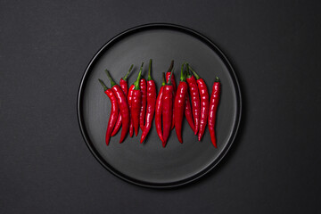 Red chili pepper on a black plate on a black background
