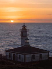 Fototapeta na wymiar Tourinan Lighthouse in Muxia, Galician coast, Spain. Twice a year, at the beginning of spring and the end of summer, Cape Touriñan becomes the last shadow for the sunset in continental Europe.
