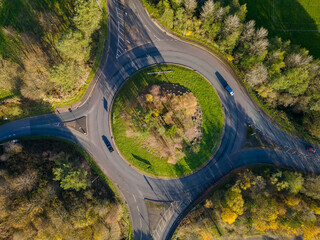 Aerial view of a small traffic roundabout on a rural road with fall (autumn) colored trees