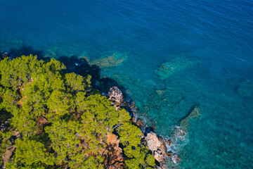 Fototapeta na wymiar Aerial top view of clear blue water sea, rocks and forest at sunset in summer Turkey