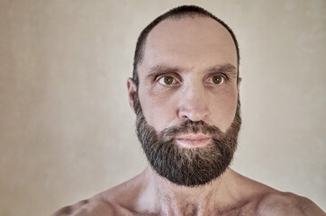 Portrait of a thinking mature naked bearded man, the man looks away