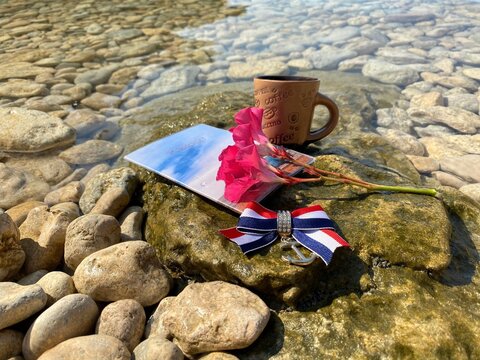 Coffee cup, passport, pink flowers on stone in the beach. Idyllic morning. Travel. Journey. Vacation. Summer.