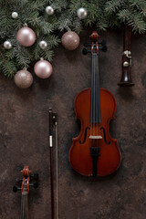 Fototapeta na wymiar Old violin and flute with fir-tree branches with Christmas decor. Christmas and New Year's concept. Top view, close-up on dark concrete background.