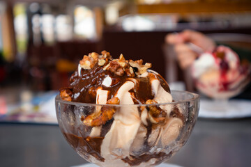 Ice cream with nuts poured over chocolate in a glass cup close-up. Soft selective focus
