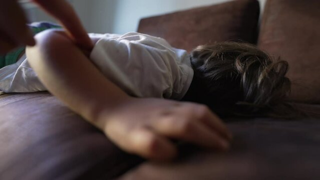 Parent trying to wake child from afternoon nap. One little boy poking kid asleep on couch. time to wake up