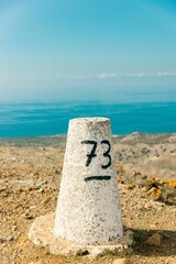 Concrete milestone with notes on the sandy ground with the background of the sea during the daytime