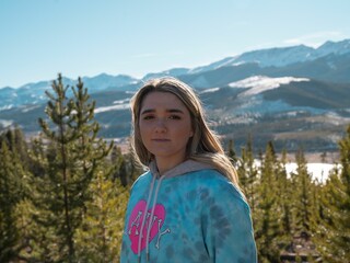 Naklejka premium Charming Caucasian blonde young girl posing against the mountain background