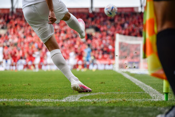 Footballer takes the corner. Detail of player's legs and the ball during soccer match.