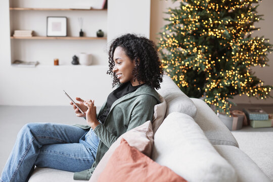 Young woman using smartphone at home during Christmas holiday, Student girl texting on mobile phone indoors, Connection, online shopping, winter lifestyle concept