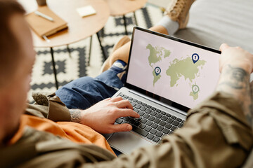 Close up of man with prosthetic leg using laptop, world map on screen