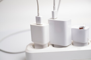 Many chargers are connected to an electrical outlet on a white background.