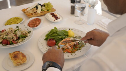 while taking a piece of fish meal. appetizers, fish dinner and wine