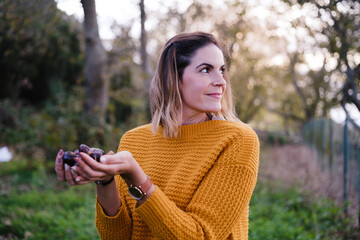 Young woman picking chestnuts during an autumn afternoon and enjoying the freedom