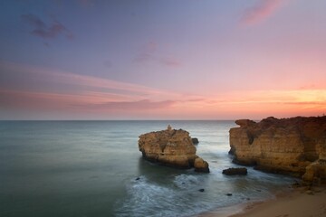 Aerial view of high cliffs in the blue ocean at mesmerizing colorful sunset, Algarve, Portugal