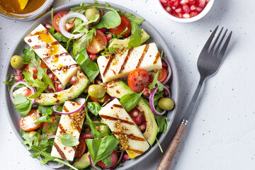 Salad with fried Halloumi cheese, cherry tomatoes, arugula and pomegranate seeds. healthy food.