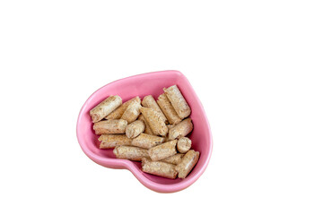 Filler for cat toilet. Pellets in pink heart-shaped saucer. Wood Pellet (Pine). Cat Litter. Isolated