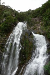 Vertical shot of a waterfall flowing from high rocky cliff