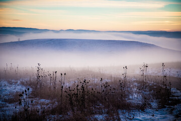 Fototapeta premium moody winter landscape with fog at sunset