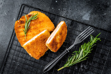 Schnitzel Cordon bleu fillet cutlet with ham and cheese. Black background. Top view