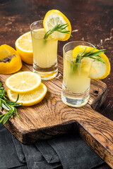 Italian limoncello liqueur and fresh lemons on a rustic wooden board. Dark background. Top view - obrazy, fototapety, plakaty