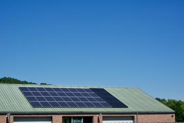 House with solar panels covering its tiled roof under a clear blue sky on a sunny day