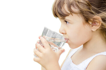 The child drinks water from a glass of isolate. Selective focus. Kid.