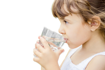 The child drinks water from a glass of isolate. Selective focus. Kid.